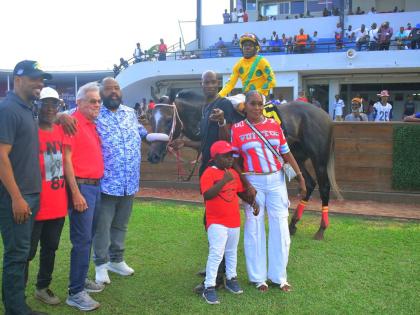 
Supreme Ventures Racing and Entertainment Limited’s chairman Solomon Sharpe (fourth left) hugs trainer Philip Feanny after his charge RIDEALLDAY, with jockey Paul Francis in the saddle, parades in the winners enclosure with winning connections following