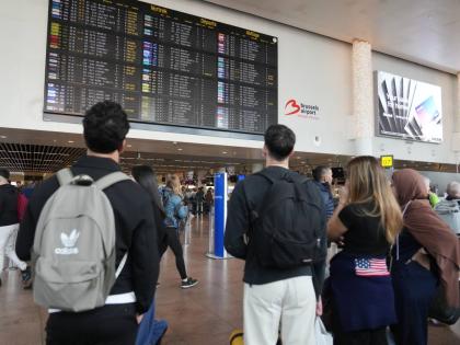 Passengers look at a departure board after several cancellations and delays as a result of reported overnight drone activity over Brussels International Airport in Zaventem.