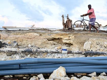 
A pedal cyclist in St Elizabeth walks with his bicycle around an area of roadway which once covered pipes and cables in the aftermath of Hurricane Melissa.  