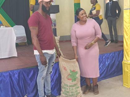 Kerensia Morrison, member of parliament for St Catherine North Eastern, handd a bag of Irish potato seeds to Guys Hill vegetable farmer Alrick Gordon.