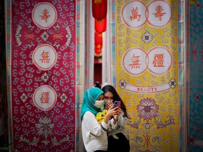 Two Malay girls check a mobile phone at a fabric installation decoration at Kwai Chai Hong, the Chinatown area in downtown Kuala Lumpur, Malaysia, Tuesday, March 30, 2021. (AP Photo/Vincent Thian, File)