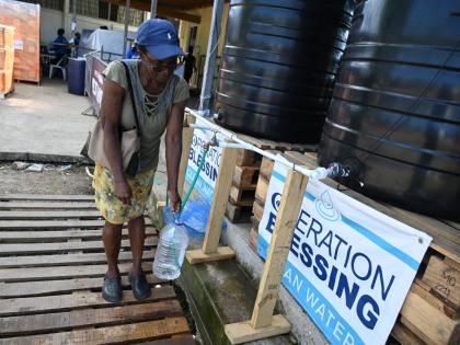 A Montego Bay resident collects water at the Operation Blessing headquarters on the Trumpet Call Ministries grounds in Montego Bay, St James.