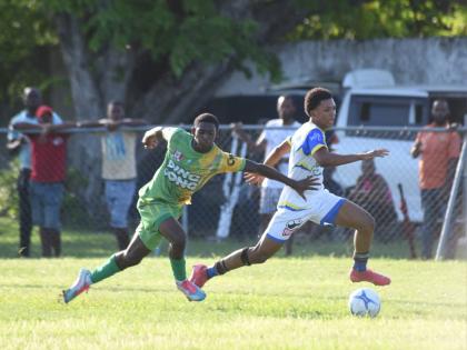 St. Elizabeth Technical High School’s (STETHS) R-Jay Newman (right) dribbles by Ocho Rios High’s Demar Tyson during their round of 16 of the ISSA daCosta Cup match at Drax Hall Sports Complex yesterday. STETHS won 3-0.