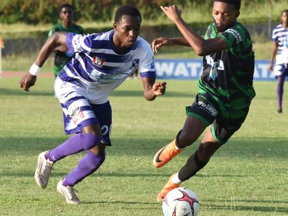 Kingston College’s Kajay Fletcher (left) dribbles by Calabar’s Payton Larmond during their ISSA/WATA Manning Cup round-of-16 football match at the Stadium East field yesterday.