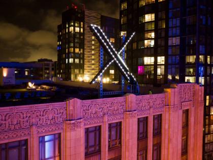 FILE - Workers install lighting on an "X" sign atop the company headquarters in downtown San Francisco on July 28, 2023.