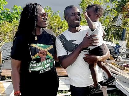 Former national basketballer and Women’s National Basketball Association player Vanessa Gidden poses with Orlando Ennis and his two-year-old son Matthew during a distribution of relief items to residents who were affected by Hurricane Melissa  in Pullet 
