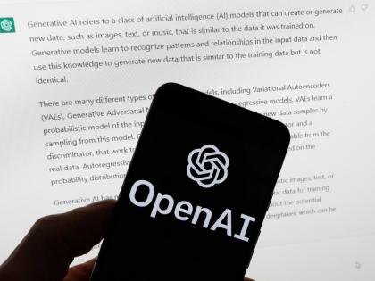 The OpenAI logo is displayed on a mobile phone in front of a computer screen with output from ChatGPT, March 21, 2023, in Boston. (AP Photo/Michael Dwyer, File)