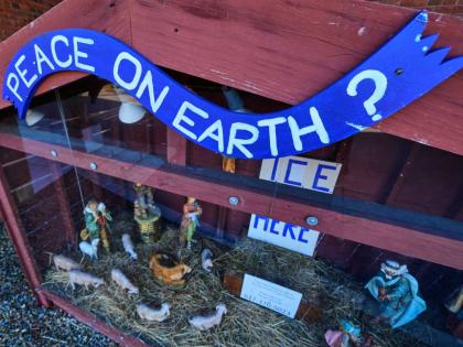 A ‘PEACE ON EARTH?’ sign is posted on the top of a nativity display, which features an ICE WAS HERE sign in the spot for the baby Jesus, outside St Susanna Church in Dedham, Mass on December 9.
