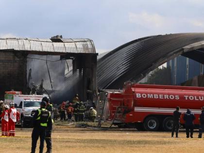Firefighters and Red Cross workers tend to the site of a plane crash near Toluca airport in San Mateo Atenco, Mexico, Monday, December 15, 2025. (AP Photo/Ramses Mercado)