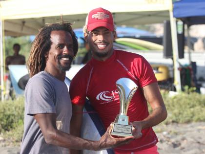 Jamaica Surfing Association competitions co-ordinator, Icah Wilmot (left), hands the National Surfing Championships winning trophy to Elishama Beckford at the Copa Beach on Sunday.