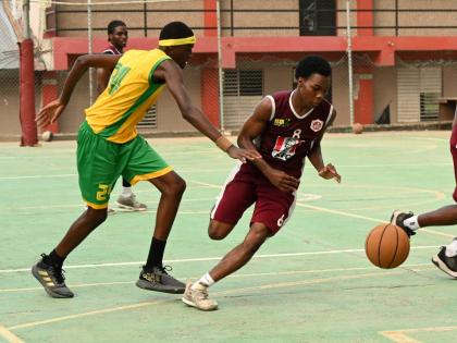Herbert Morrison Technical High School’s Ryan Jurdine (right) dribbles by Ocho Rios High School’s Michael Rubie during their ISSA Schoolboy Basketball match at the Herbert Morrison court on Monday.