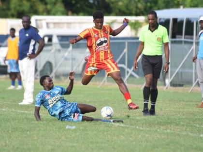 Cornwall College’s Shakeem Gibson hurdles a tackle by McGrath High’s Kepling McFarlane (left) during their ISSA Ben Francis KO semi-final at Drax Hall Sports Complex  yesterday. Cornwall won 2-0.