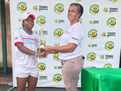Jade Fearon (left) collects one of her trophies from Ann Marie Maxwell, All Jamaica Tennis administrator,  during the All Jamaica Tennis Championship held at the Eric Bell National Centre on Saturday, December 20, 2025. Fearon won the under-16 and under-18