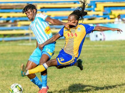 Harbour View’s Alonzo Peart (right) throws himself into a tackle against Waterhouse’s Kvist Paul during a Jamaica Premier League fixture at the Harbour View Mini-Stadium in Kingston yesterday. The game ended 1-1.