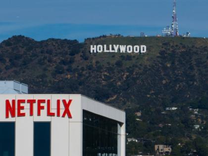 A Netflix sign is displayed atop a building in Los Angeles, on December 18, 2025, with the Hollywood sign in the distance. (AP Photo/Jae C. Hong, File)