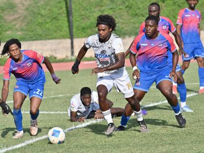 Cavalier’s Chad James sprints away from a mid-pitch melee with Dunbeholden’s Nathaniel Taj Waul (left) and teammate Christopher Matthews in chase during yesterday’s Jamaica Premier League game at Stadium East. Cavalier won 5-1.