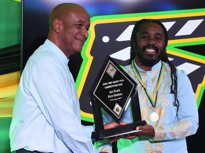 Lenford Salmon (left), executive director, Jamaica Cultural Development Commission, presents Omaall Wright with the  first place trophy after he won the Fiwi Short Film Competition.