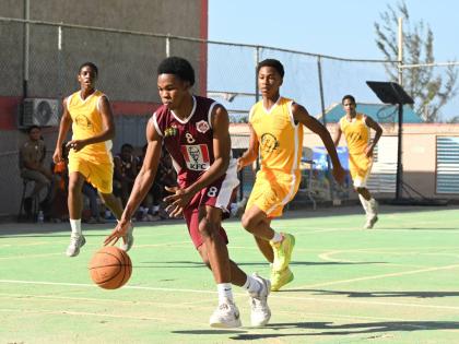 Herbert Morrison Technical High School’s Ryan Jurdine (front) dribbles away from Garvey Maceo High School’s Nicade Bachan (right) during their ISSA Schoolboys Rural Basketball quarterfinal match at the Herbert Morrison court yesterday.
