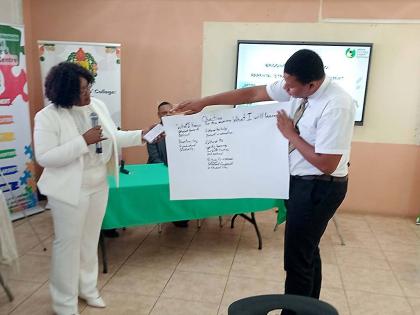 Kaysia Kerr (left), chief executive officer of the National Parenting Support Commission (NPSC),  looks on as Kyle Paul Stephenson (right) explains to the audience the objectives he hopes to be achieved by the end of the workshop.