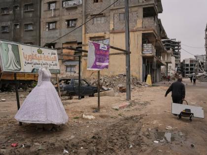 A man walks past a wedding dress displayed on a street next to a bridal shop in Khan Younis, southern Gaza Strip.