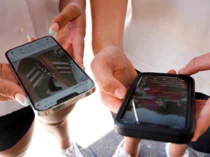 Young people use their phones to view social media in Sydney, November 8, 2024. (AP Photo/Rick Rycroft, File)