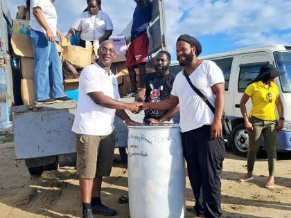 Chief Executive Officer of the Croydon Black Minority Ethnic (BME) Forum, Dr Andrew Brown (left), hands over a barrel of tools and building supplies to community members Michael (centre) and Ridge Harvey (right) in Parottee, St Elizabeth, on January 22. Th