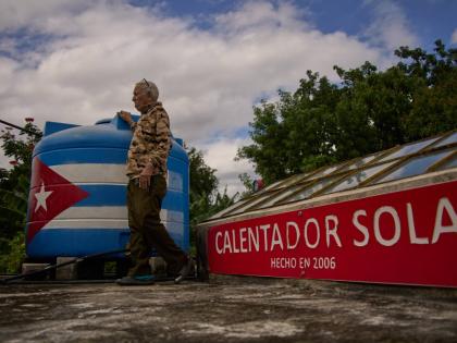 Felix Jose Morfi stands by his solar-powered water heater system he set up on his home’s roof in Regla, Havana province, Cuba, on January 29.