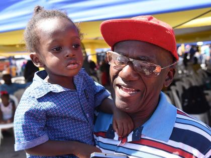 Liston Morrison (right), president of the International Community of Churches, who is visually impaired, holds his two-year-old son Mathias Morrison at the Ministry of Justice, Legal Aid Council’s Justice Fair for Persons with Disabilities in Spanish Tow