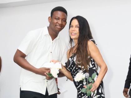 Producer Debra Ehrhardt presents Jamar Grant with his first-place prize for ‘In Search of More-Rock’ at the fifth annual What’s Your Story, Jamaica? Storytelling Competition.