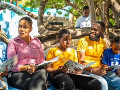 Gail Moss-Solomon, general counsel & chief corporate secretary (left) and Kenny-Dee Bryan, human resource officer, Consumer Brands Limited, and GK Earth365 Ambassador (second right) join students from the Jessie Ripoll Primary School in a read-aloud of the