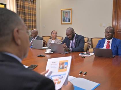Prime Minister, Dr Andrew Holness (left), listens attentively to Executive Director of the National Identification and Registration Authority (NIRA), Dr Warren Vernon (right), during a meeting held recently at the Office of the Prime Minister.