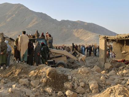 Local residents and civil defense workers look on as a bulldozer clears the rubble of a house hit by a cross-border Pakistani army strike in the Behsud district of Nangarhar province, Afghanistan, on February 22, 2026. 