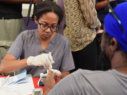 Dr Shauna Martin Lee (left) conducts a diabetes test on a patient at the Kingston and St Andrew Municipal Corporation Health Expo, held on Wednesday at the Jubilee Commercial Centre, West Parade, downtown Kingston.