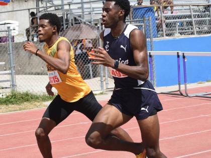 Rojay Black (right) of Jamaica College and Excelsior High’s Kishawn  Hoffman in a close battle during heat one of the Class One boys 400m hurdles on day one of the Corporate Area Athletics Championships at Ashenheim Stadium last Friday. Black won in 51.4
