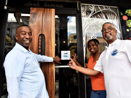 Sherina Whyte (centre) , co-founder of Waah Gwaan Café, affixes the ‘Keep It Clean’ sticker decal on the door of her business place. Sharing in the moment are Councillor Andrew Swaby (left), mayor of Kingston and chairman of the Kingston and St Andrew