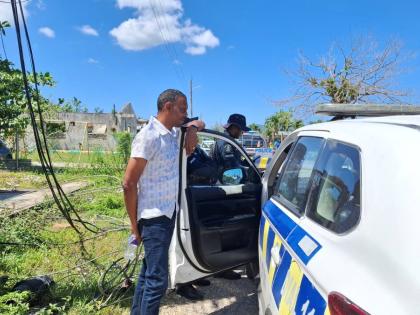Member of Parliament Dwayne Vaz speaks with members of the Jamaica Constabulary Force after addressing residents in Hertford amid ongoing concerns about road conditions.