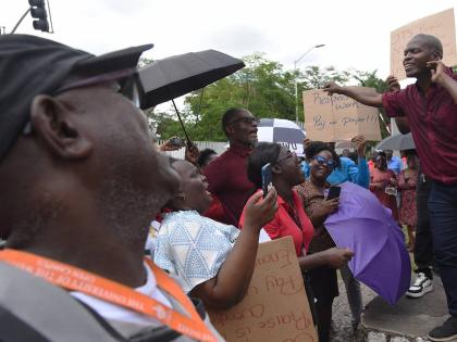 Dennis Samuels (right), Union Representative at the University of the West Indies (UWI), addresses employees at both the University of the West Indies (UWI) and University Hospital of the West Indies (UHWI) who demonstrated outside the gates of the UWI for