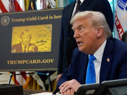 A poster showing the Trump Gold Card is seen as President Donald Trump signs executive orders in the Oval Office of the White House, September 19, 2025, in Washington. (AP Photo/Alex Brandon, File)