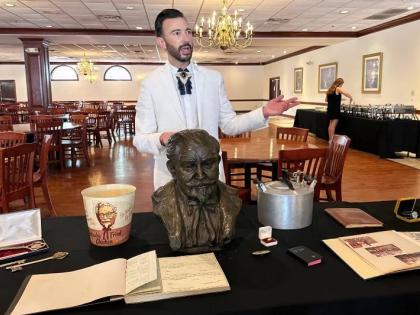 Auctioneer Jonathan Klunk gestures to a display of personal items owned by KFC founder Harland Sanders, Wednesday, July 22, 2026, in Shelbyville, Ky. (AP Photo/Dylan Lovan)