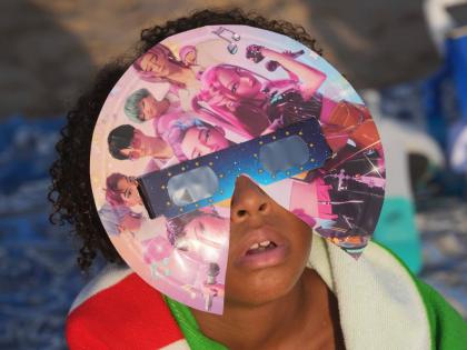 A beachgoer wearing special eclipse glasses looks up during the beginning phase of a solar eclipse at Puerto de Sagunto beach near Valencia, Spain, Wednesday.