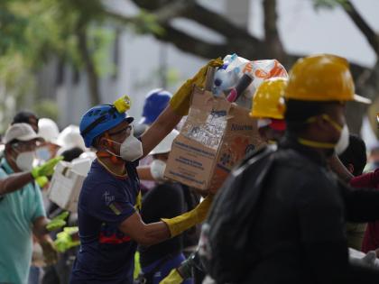 Rescuers pass food packages for rescue teams and volunteers searching through the rubble four days after an earthquake hit Cali, Colombia, last Friday.