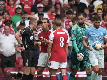 Referee Sam Barrott, left, discusses with Arsenal's Riccardo Calafiori, second left, during the FA Community Shield final soccer match between Arsenal and Manchester City in Cardiff, Wales, Sunday, Aug.16, 2026. (AP Photo/Alastair Grant)