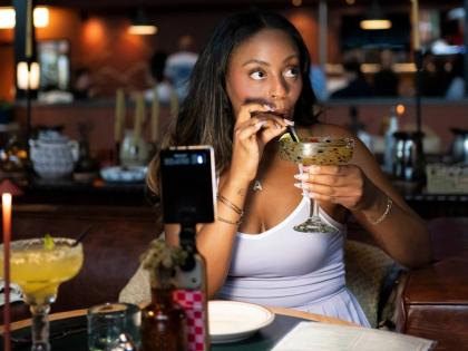 Phoenix-based content creator Aiesha Beasley films herself as she samples a margarita during the grand opening of Padeland, a venue for the racket sport padel in Chandler, Arizona, August 13. 