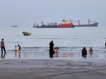 People spend time at a beach as commercial vessels are anchored in the Strait of Hormuz off Bandar Abbas, Iran, August 5.
