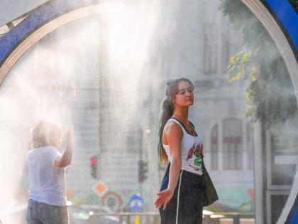  A woman pauses while she walks through a water mist machine installed by city administration to assist people in coping with the heat in Bucharest, Romania, on August 6.