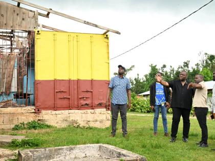 Parliamentary Secretary in the Ministry of Education, Skills, Youth and Information, Marlon Morgan (centre), and Principal of Maggotty High School, Sean Graham (second right), inspect a damaged structure on the school compound during a Back-to-School tour 