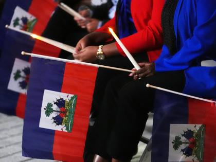 FILE - People hold Haitian flags and candles during a vigil at the Little Haiti Cultural Complex after a federal judge blocked the Trump administration from ending temporary immigration status, or TPS, for Haitians, Feb. 3, 2026, in North Miami. (AP Photo/