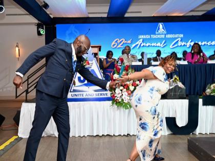 Immediate Past President Mark Malabver passes the baton to La Sonja Harrison, the newly installed president of the Jamaica Teachers’ Association, during the investiture ceremony at the association’s 62nd Annual Conference at the Ocean Coral Spring Hote