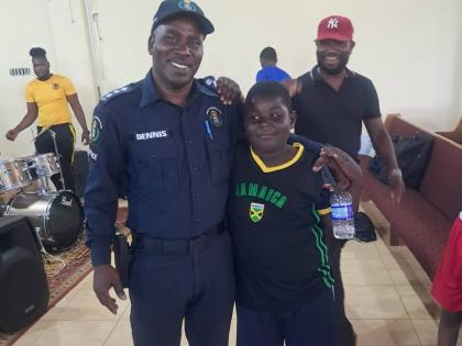 Superintendent Odaine Dennis, commanding officer for the Manchester Division, greets and poses with a young camper last week.