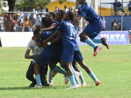 The Manning’s School goal keeper Mikhail Romans (left) is swarmed by his teammates after his heroics help them defeat Dinthill Technical High School in an ISSA daCosta Cup semi-final penalty shootout at the STETHS Sports Complex in 2024.